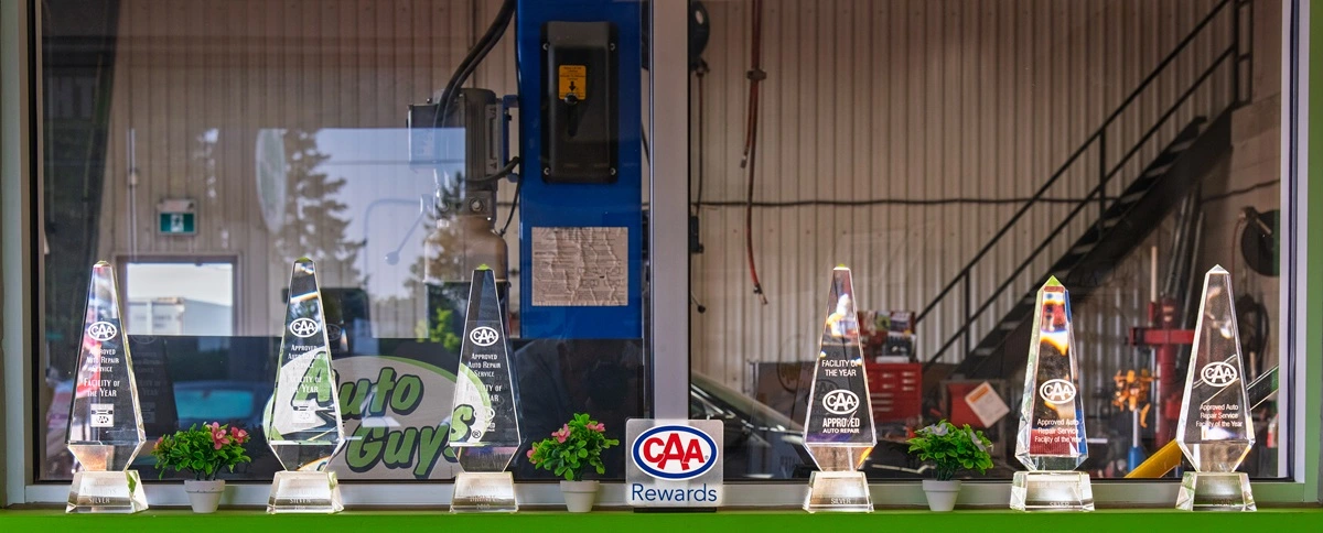 Six CAA awards on display in front of a window to the Auto Guys shop